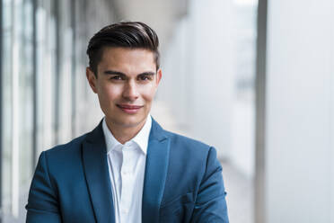 Confident businessman standing in corridor - DIGF15674