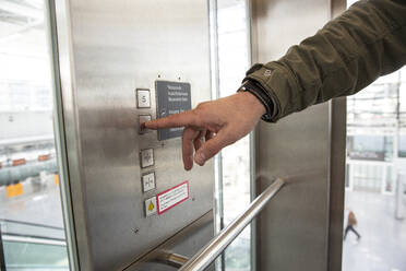Mann drückt Knopf im Aufzug - AUF00710