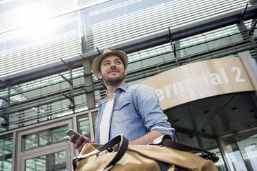 Young man with luggage arriving from airport terminal - AUF00734