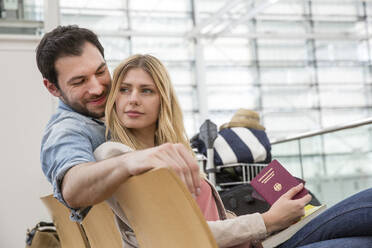 Young couple with passport waiting in airport departure area - AUF00736