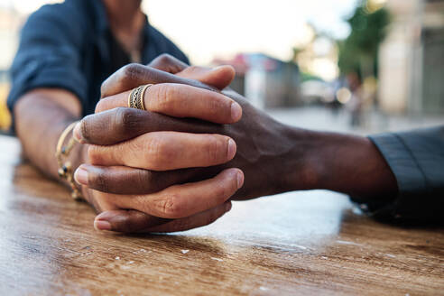 Multi ethnic gay couple holding hands on table at sidewalk cafe - AGOF00127