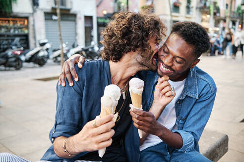 Smiling gay couple romancing while holding ice cream cones - AGOF00134