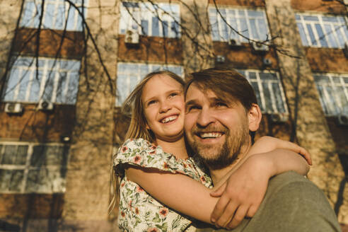 Vater und Tochter schauen an einem sonnigen Tag in der Stadt weg - EYAF01622