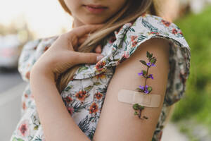 Arm eines Mädchens mit Blume und Pflaster - EYAF01623