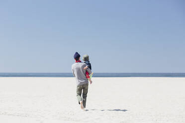 Father carrying son while walking on beach - ACTF00042