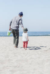 Sohn geht mit Vater am Strand spazieren und hält sich an den Händen - ACTF00050
