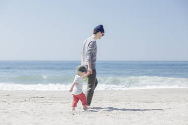Vater und Sohn halten sich an den Händen und gehen am Strand spazieren - ACTF00053