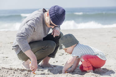 Vater und Sohn graben Sand beim Spielen am Strand - ACTF00057