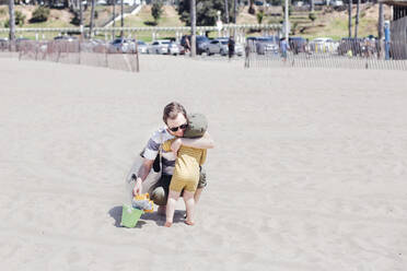 Affectionate father hugging son at beach - ACTF00084