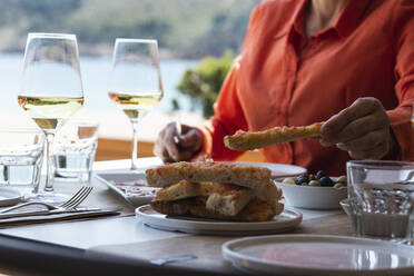 Ältere Frau mit Essen am Tisch in einem Strandrestaurant - PNAF01769