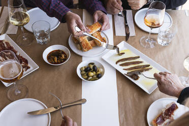 Friends eating Spanish food at table in restaurant - PNAF01786