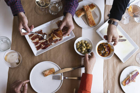 Male and female friends eating food at table in restaurant - PNAF01788