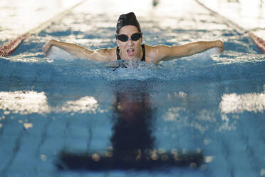Weibliche Athletin schwimmt im Schmetterlingsstil im Pool eines Fitnessstudios - JSMF02252