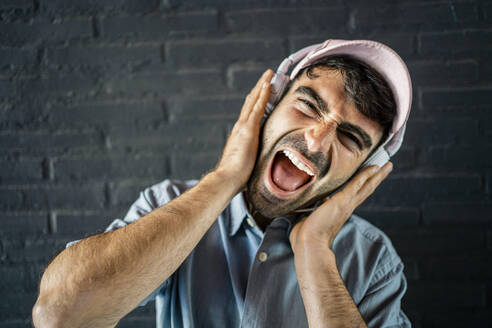 Young man making face in front of wall - RCPF01128