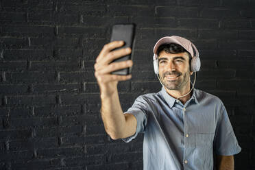 Smiling man taking selfie through smart phone - RCPF01131