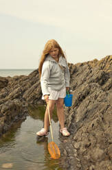 Curious girl with fishing net at tidal pool - AJOF01418