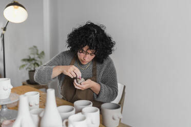 Weibliche Kunsthandwerkerin malt ein Kunstprodukt während der Arbeit in der Werkstatt - ASSF00082