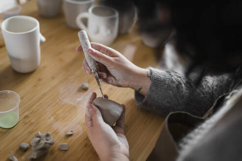 Female artist with hand tool and clay at workplace - ASSF00096