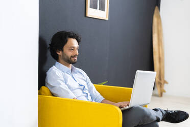 Junger männlicher Unternehmer arbeitet am Laptop im Büro - GIOF12832