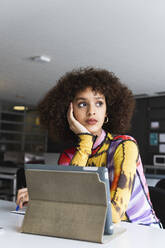 Thoughtful female student with hand on chin looking away in university - PNAF01814