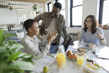 Business people talking over breakfast in office meeting - CAIF30491