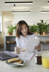 Geschäftsfrau bei der Durchsicht von Papierkram in der Bürolounge - CAIF30492