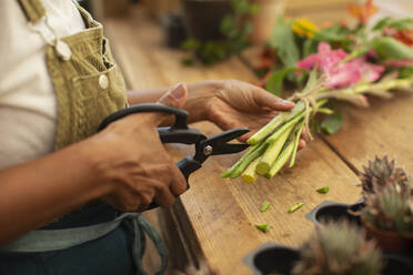 Floristin, die Blumenstiele mit einer Schere abschneidet - CAIF30519