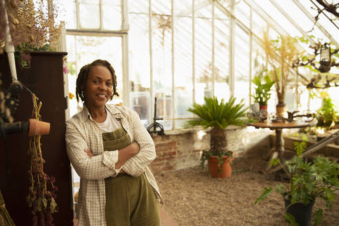 Portrait confident female garden shop owner in greenhouse - CAIF30521