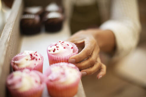 Nahaufnahme Hand greift nach rosa Cupcake - CAIF30568