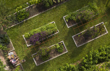 Blick von oben auf ein Paar im üppigen Sommergarten mit Hochbeeten - CAIF30577