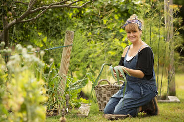 Porträt einer selbstbewussten Frau bei der Ernte von frischem Lauch im Garten - CAIF30601