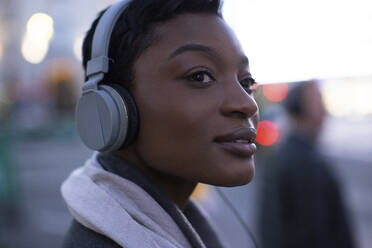 Close up beautiful young woman listening to music with headphones - CAIF30622