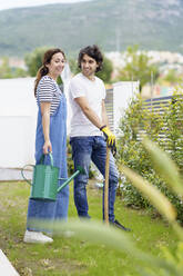 Lächelndes mittleres erwachsenes Paar im Garten stehend - JSMF02271