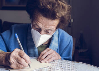 Senior woman writing on paper at home - JCCMF02673