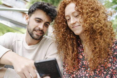 Young man with girlfriend using smart phone - JCZF00760