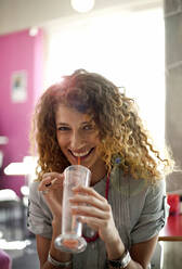 Curly haired woman drinking juice at cafe - AJOF01430