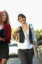 Lächelnde Kolleginnen, die beim Gehen auf der Straße wegschauen - AJOF01432