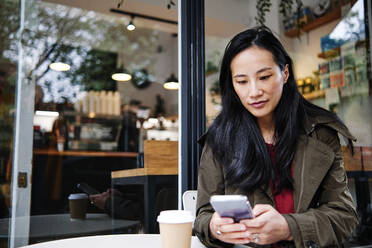 Frau benutzt Mobiltelefon in einem Cafe - ASGF00353