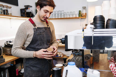 Männlicher Besitzer bereitet Kaffee im Geschäft zu - ASGF00390