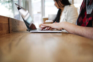 Frau benutzt Laptop mit Freundin in einem Café - ASGF00401