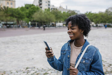 Lächelnde Frau mit Smartphone in der Stadt - XLGF01992