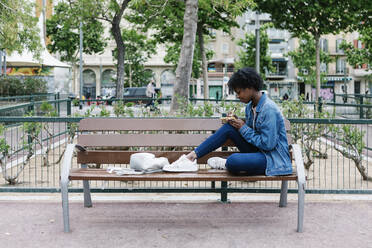 Afro-Frau, die auf einer Bank sitzend schreibt - XLGF01996