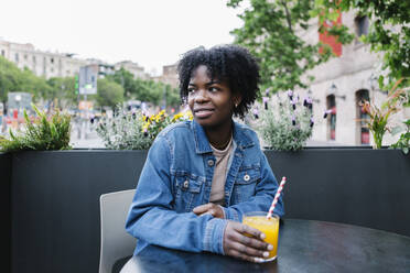 Smiling woman looking away while sitting at cafe - XLGF02012