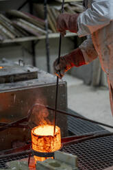 Schmied schmilzt Bronze in einem Behälter in der Industrie - OCMF02127