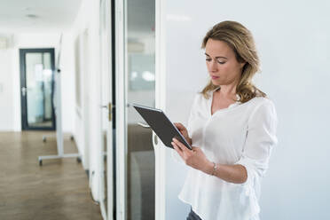 Geschäftsfrau mit digitalem Tablet bei schalldichter Kabine im Büro - DIGF15693