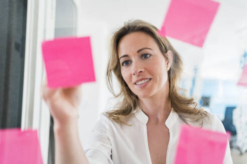 Businesswoman writing strategy on adhesive note at office - DIGF15703