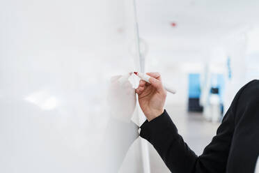 Businesswoman writing on whiteboard at office - DIGF15731