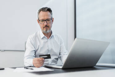 Geschäftsmann mit Laptop und Kreditkarte im Büro - DIGF15827