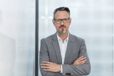 Male entrepreneur with arms crossed standing in office - DIGF15836