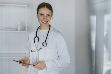 Mid adult female doctor standing with digital tablet - MFF07968